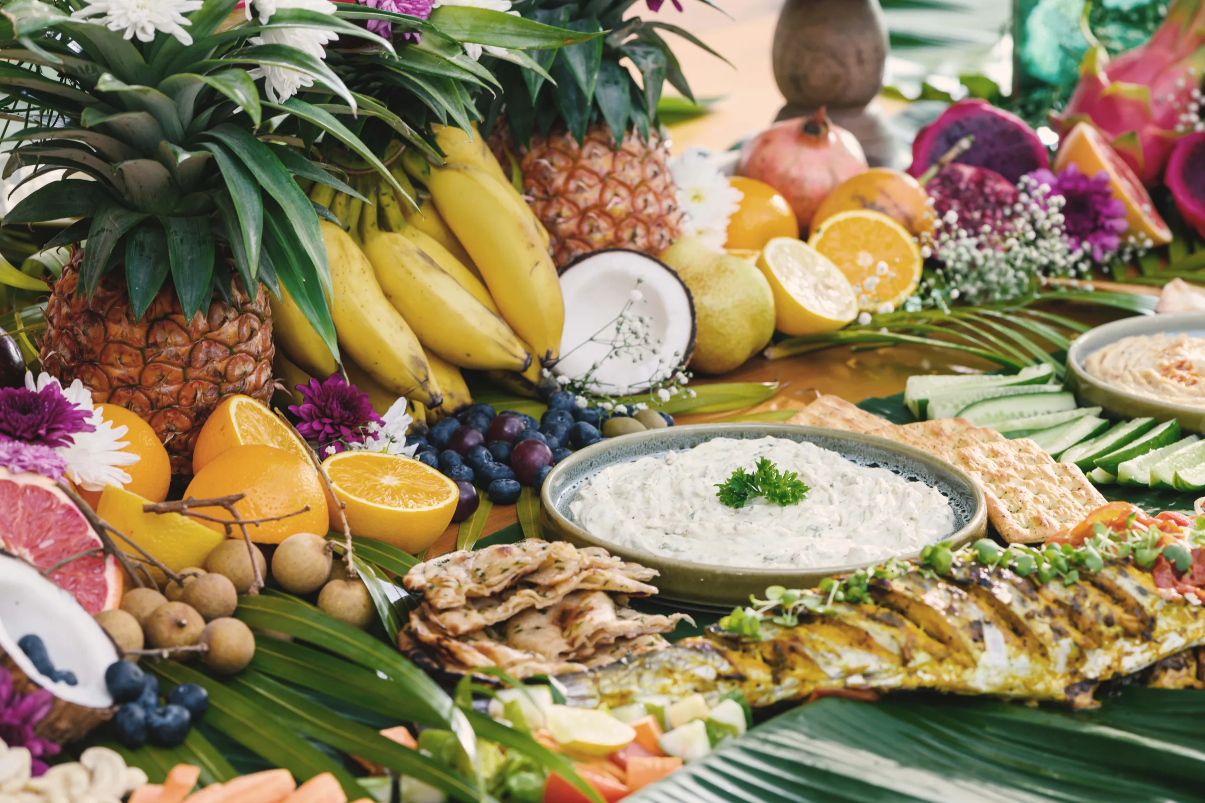 Fruit, dips and grilled fish arranged on banana leaves
