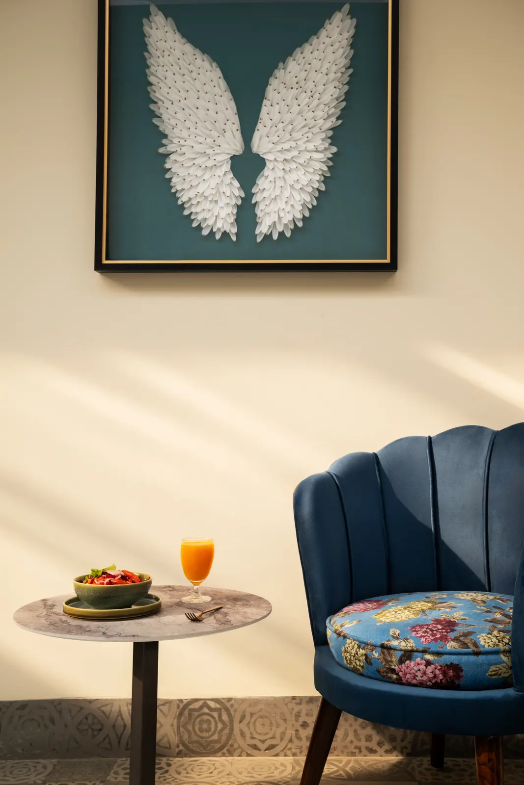 A blue chair, small table and feather artwork