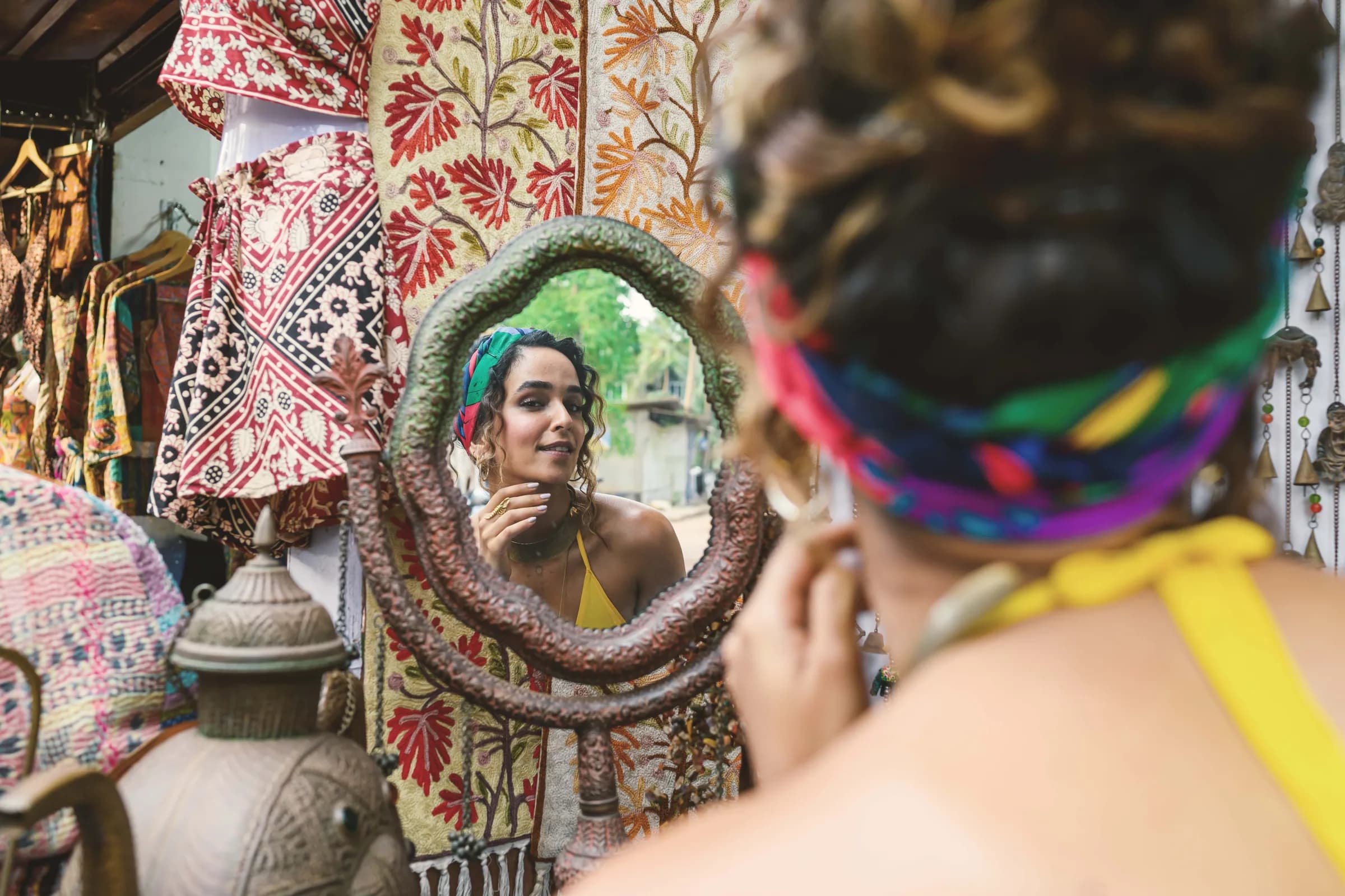 A shopper looking into an ornate mirror among patterned textiles