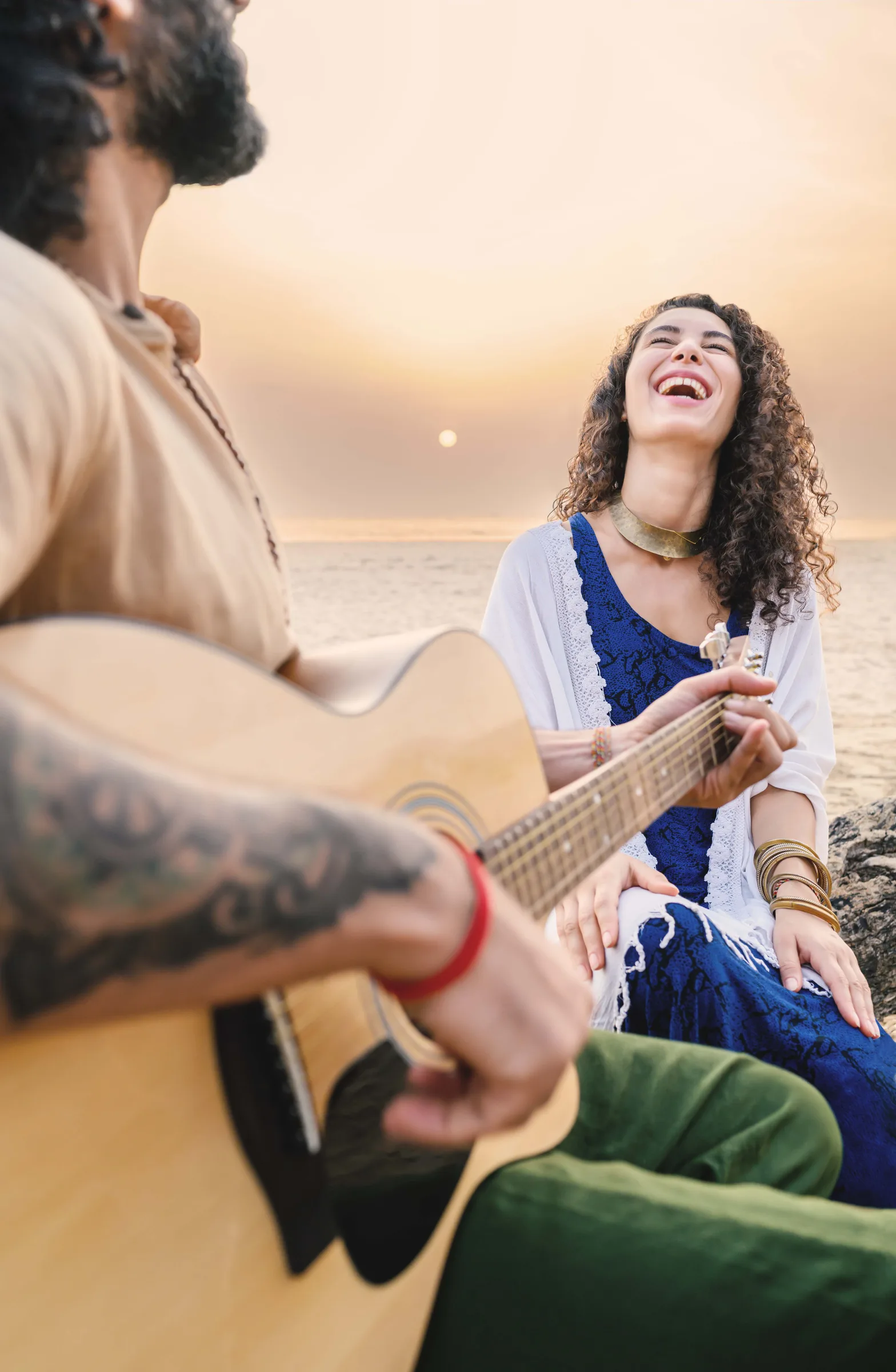 Two people with a guitar beside the sea